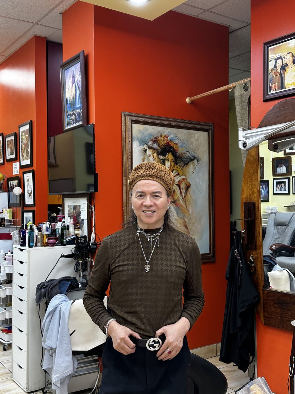 The owner of Rus 2 Our standing in the salon in front of the wall of framed photos