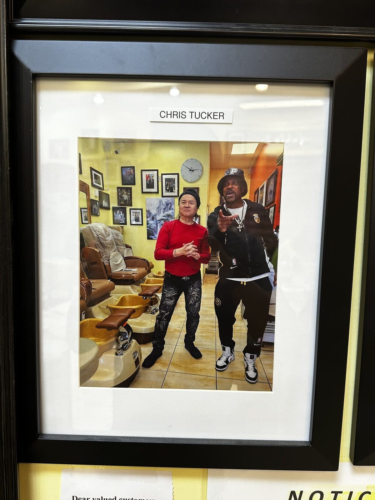 Framed photo on the salon wall, labeled Chris Tucker, taken beside the pedicure chairs
